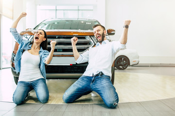 The successful visit to the dealership. Happy young couple chooses and buying a new car for the...