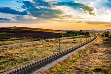 Fototapeta na wymiar Sunset diagonal railway with scenery tranquil landscape background with colorful evening cloudy sky, Dimitrovgrad, Bulgaria