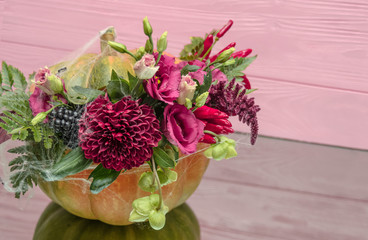 Halloween pumpkin with flowers and leaves on mirrow table.