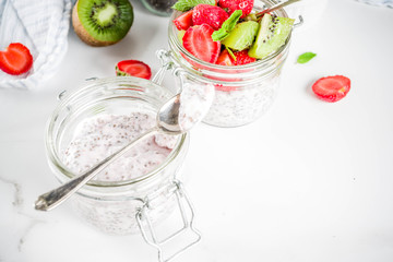 Healthy dietary vegan breakfast, yoghurt with chia seeds and fresh fruits, strawberries, kiwi.White marble background copy space