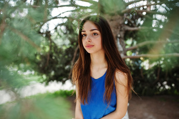 Teenage girl in blue dress posed outdoor at sunny day.