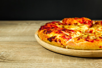 Pizza Margarita with mozzarella cheese on a wooden table.