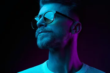 Neonlicht-Studio-Nahaufnahme eines ernsthaften Mannmodells mit Schnurrbart und Bart in Sonnenbrille und weißem T-Shirt © monchak