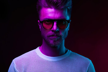 Neon light portrait of serious man model with mustaches and beard in sunglasses and white t-shirt
