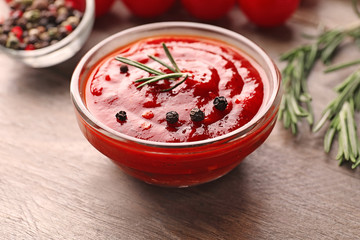 Bowl of delicious tomato sauce with spices on wooden table