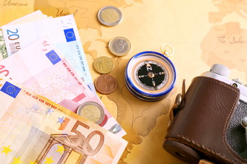 Photo camera, compass and money on vintage world map. Travel planning concept