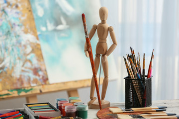 Set of tools and paints of professional artist on table in workshop