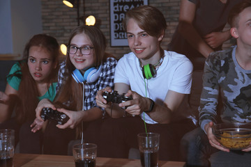 Teenagers playing video games at home late in the evening