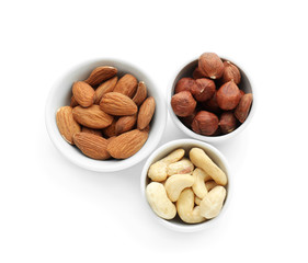Bowls with different nuts on white background