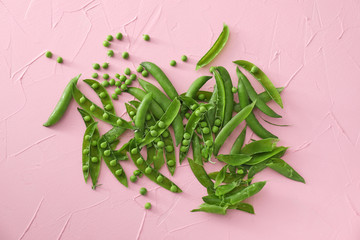 Pods with fresh green peas on color background