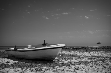 Naklejka premium Wooden boat in the sand of the beach and with a tropical landscape.Photo black and white contrast.