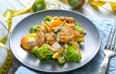 Tasty chicken salad with vegetables and measuring tape on wooden table. Diet food