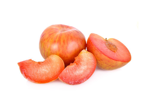 whole and sliced fresh pluot on white background