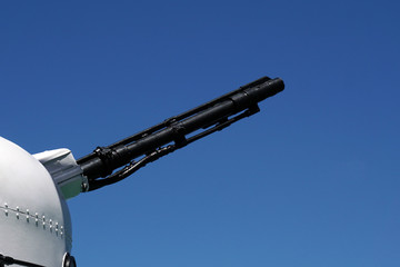 Fototapeta premium Muzzle barrel of naval ship artillery gun on a blue sky background. copy space, selective focus, narrow depth of field
