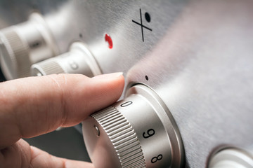 Male Hand On Stove Controls With Heat Level 0