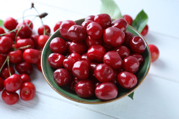 Bowl with tasty ripe cherries on wooden background