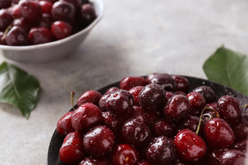 Plate with tasty ripe cherries on grey background