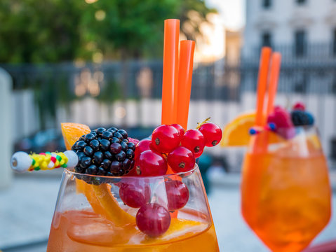 Apperol spritz cocktail in misted glass with berries and straw. Selective focus.