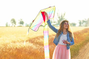 Beautiful young woman with kite in a field