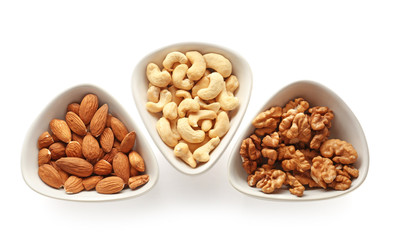 Bowls with tasty nuts on white background