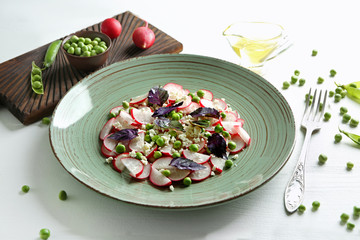 Plate with green peas salad on light table