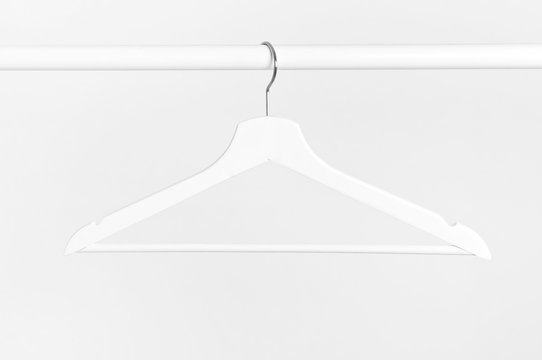 One white wooden hanger without clothes on background of white wall. Soft focus. Store concept, sale, design, empty hanger.