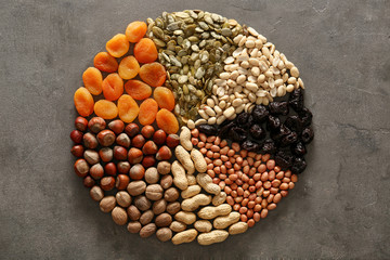 Composition with various nuts and dried fruits on grey textured background