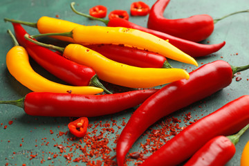 Fresh and dried chili peppers on color background