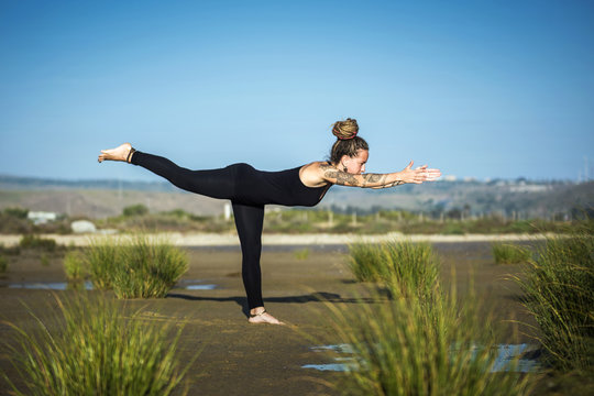 Woman on Los Lances beach doing warrior III yoga pose, The Strait Natural Park, Tarifa, Cadiz, Andalusia, Spain