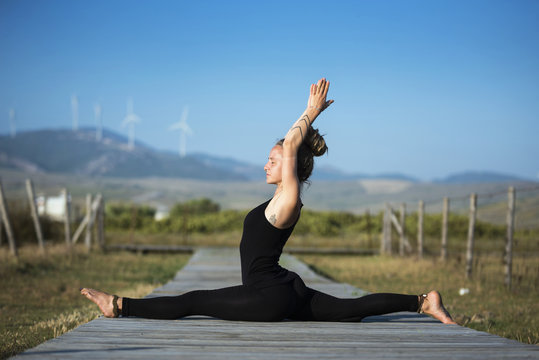 Woman on Los Lances beach doing front splits yoga pose, The Strait Natural Park, Tarifa, Cadiz, Andalusia, Spain