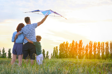 Happy family flying kite outdoors