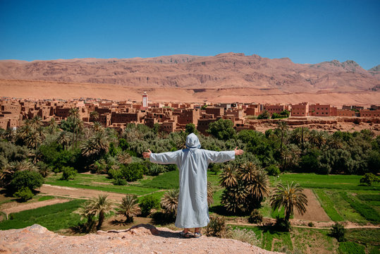Man standing with his arms outstretched near a kasbah, Ouarzazate, Morocco