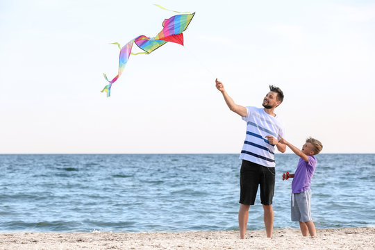 Father and his son with kite near sea