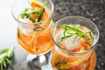Glasses with fresh cold grapefruit cocktail and rosemary on table