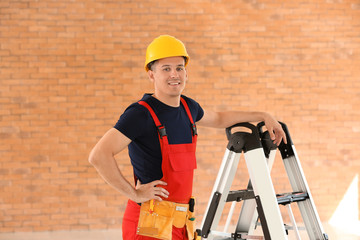 Electrician with tools and ladder in new empty apartment