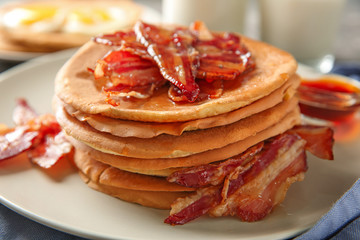 Plate with tasty pancakes and bacon on table, closeup