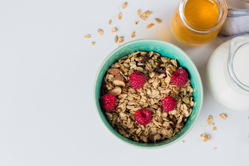 Healthy breakfast. Oat granola with nuts and raspberry, milk and honey on white background, top view
