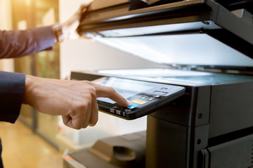Close-up bussiness man Hand press button on panel of printer, printer scanner laser office copy machine supplies start concept.