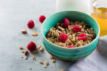 Healthy breakfast. Oat granola with nuts and raspberry, milk and honey on white concrete background, copy space