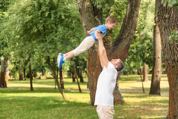 Happy father playing with son in green park