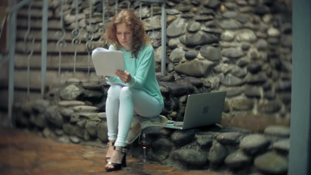 Woman with laptop and documents on the background of a stonewall wall