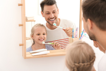 Little girl and her father brushing teeth in bathroom