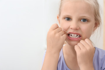 Little girl flossing teeth in bathroom