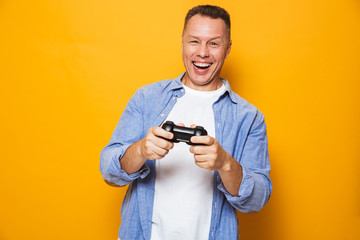 Man isolated over yellow background play games with joystick.