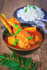 Curry chicken with rice served in a bowl over wooden background.