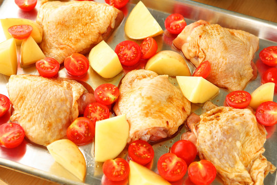 Overhead of chicken dinner with potatoes and cherry tomatoes ready for the oven