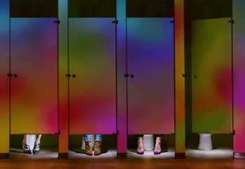 Feet under rainbow bathroom stall doors