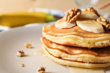 Plate with tasty pancakes, walnuts and sliced banana, closeup