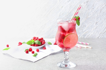 Glass of fresh raspberry mojito on table