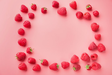 Frame made of ripe aromatic raspberries on color background